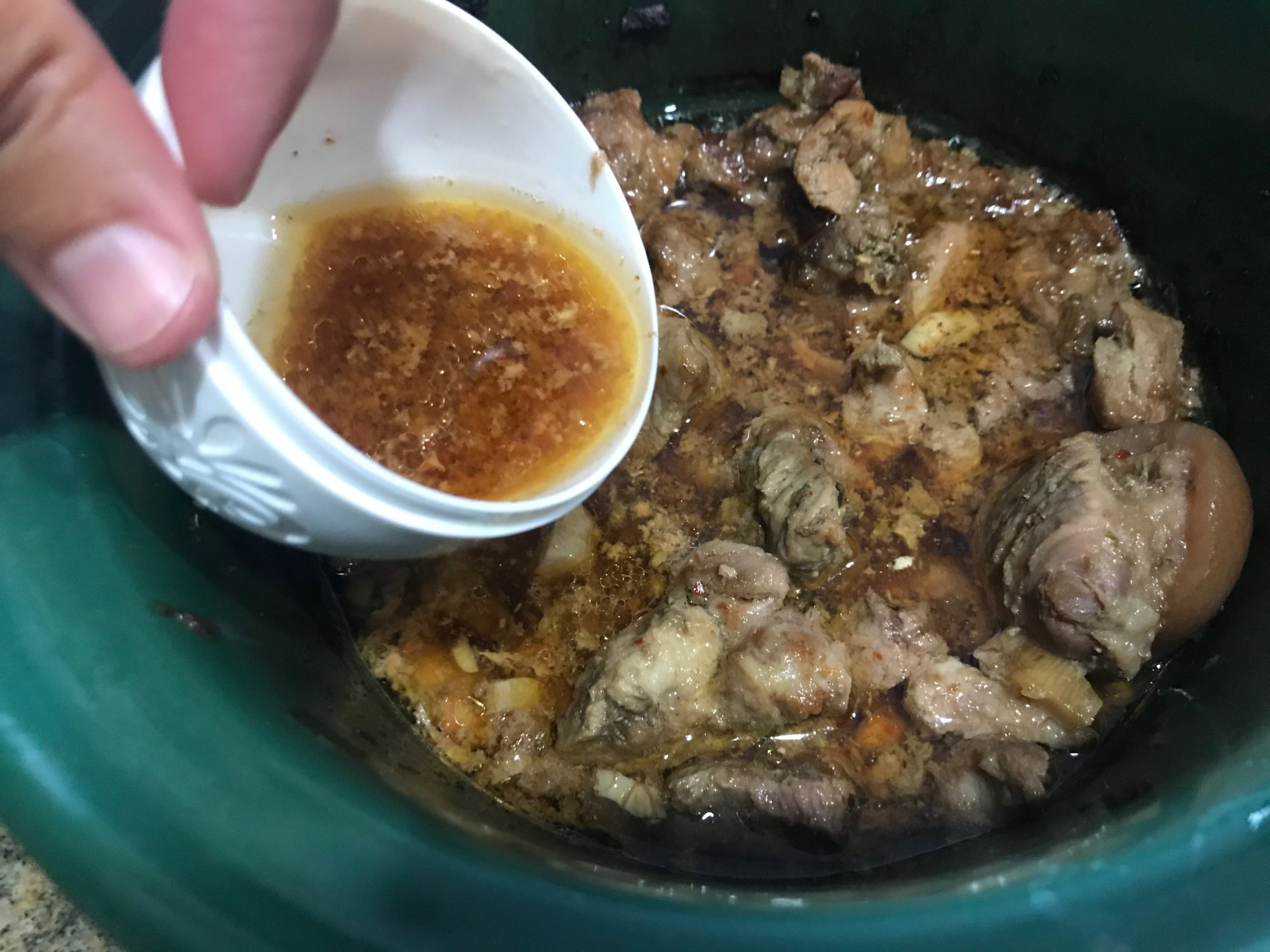 taking liquid out of the cooked pork to add to the rice