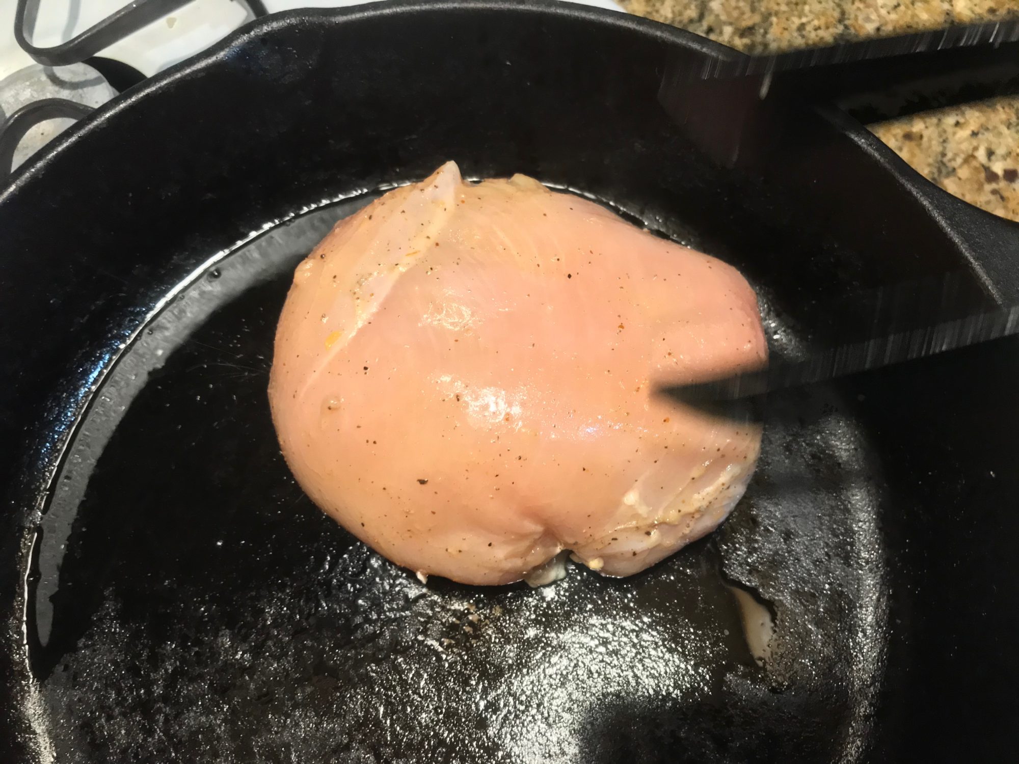 adding the chicken breast to the cast iron to brown it