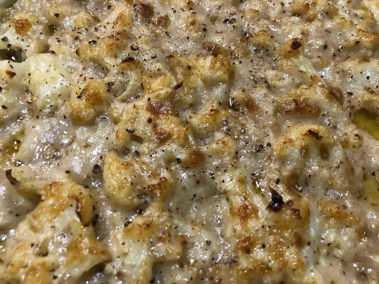 close up of cauliflower cheese in the cast iron after baking
