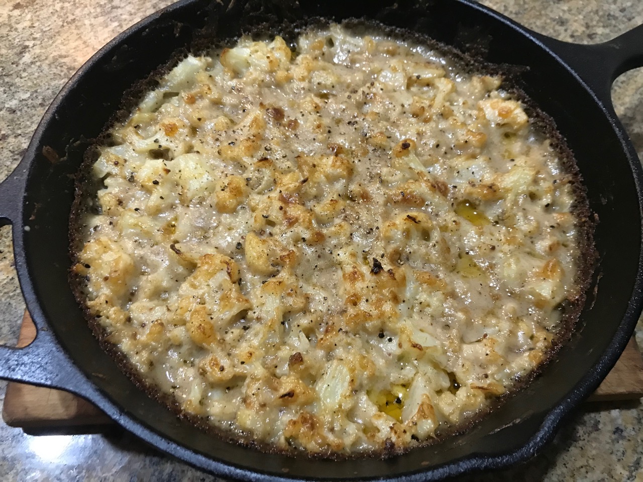 whole pan shot of cauliflower cheese in the cast iron after baking