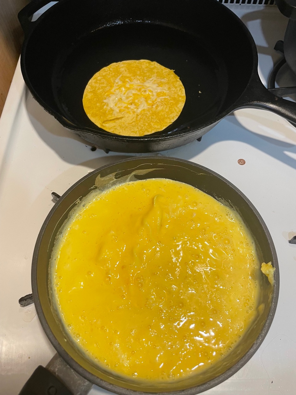 scrambling eggs and warming up tortillas, pan shot